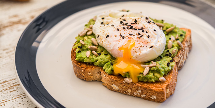 Avocado on wholegrain toast topped with a poached egg and a sprinkle of sesame seeds