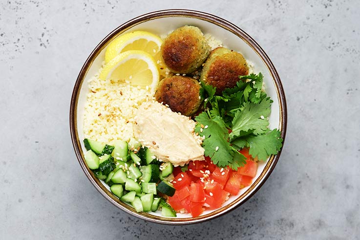 A bowl with falafels and fresh salad ingredients