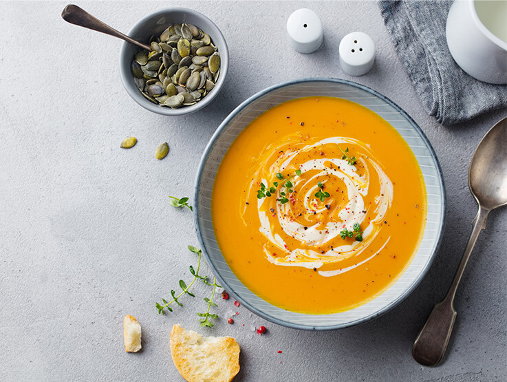 Pumpkin and carrot soup topped with a sprinkling of toasted pumpkin seeds