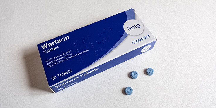 A blue and white pharmaceutical packet of Warfarin tablets.