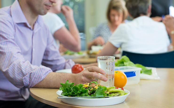 A man eats a heart healthy lunch consisting of plenty of vegetables and fruit.