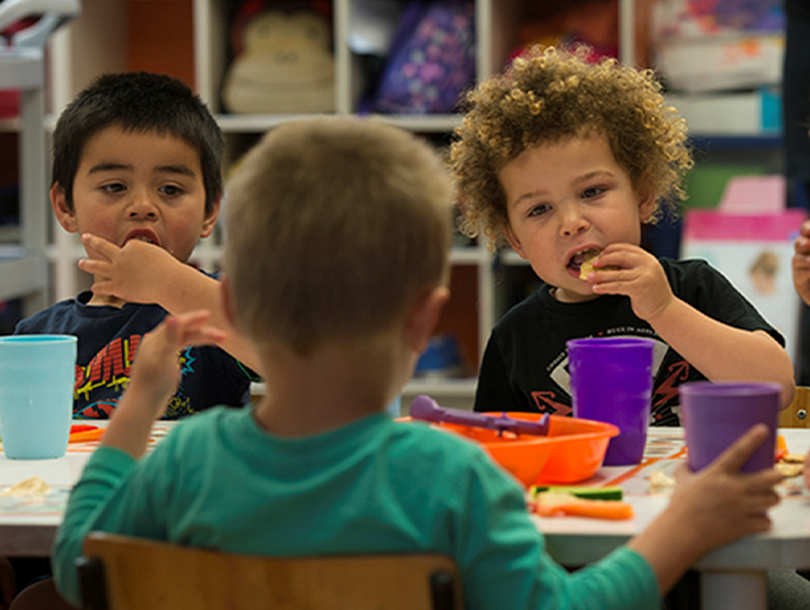 Three pre school children eating lunch