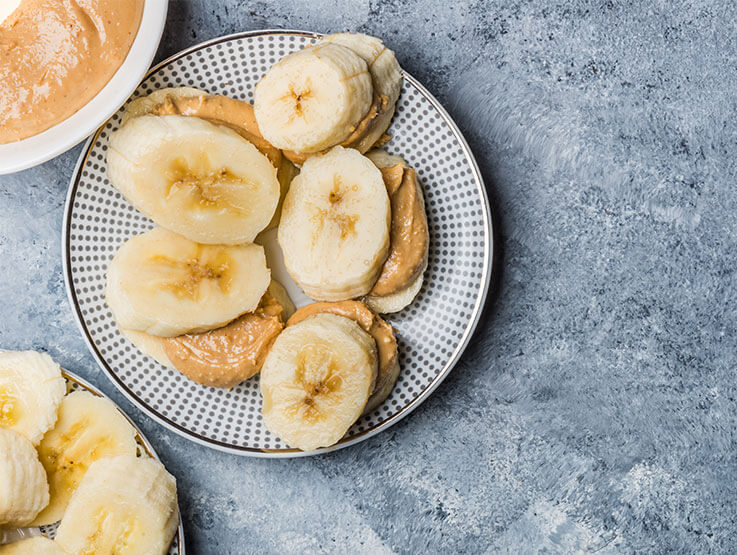 Light Healthy Snack made from Banana Slices and peanut Butter on wholegrain toast on Grey Background